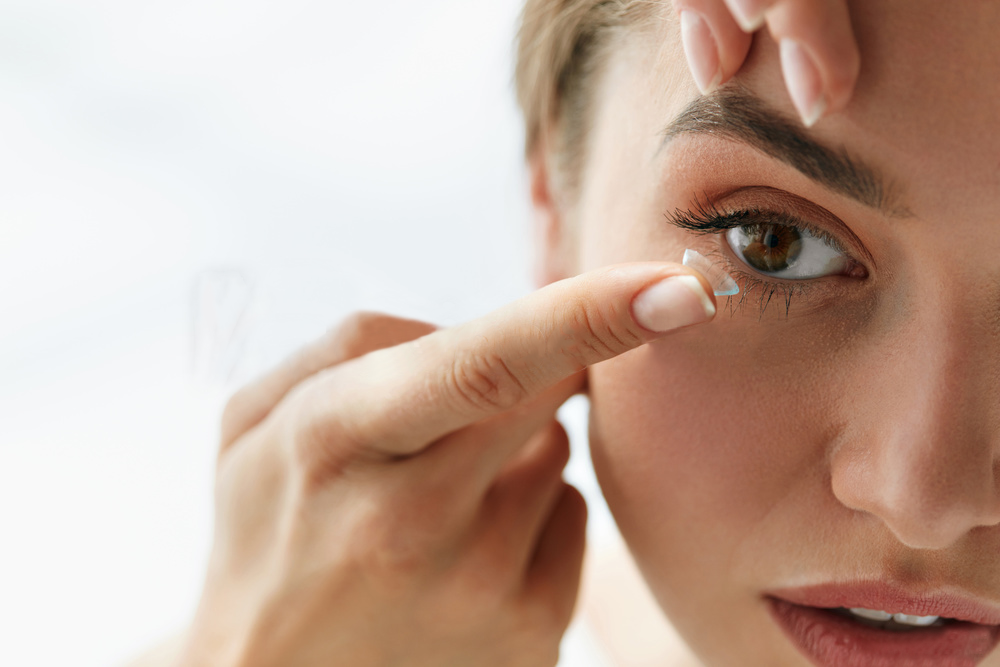Image of woman applying a contact lense